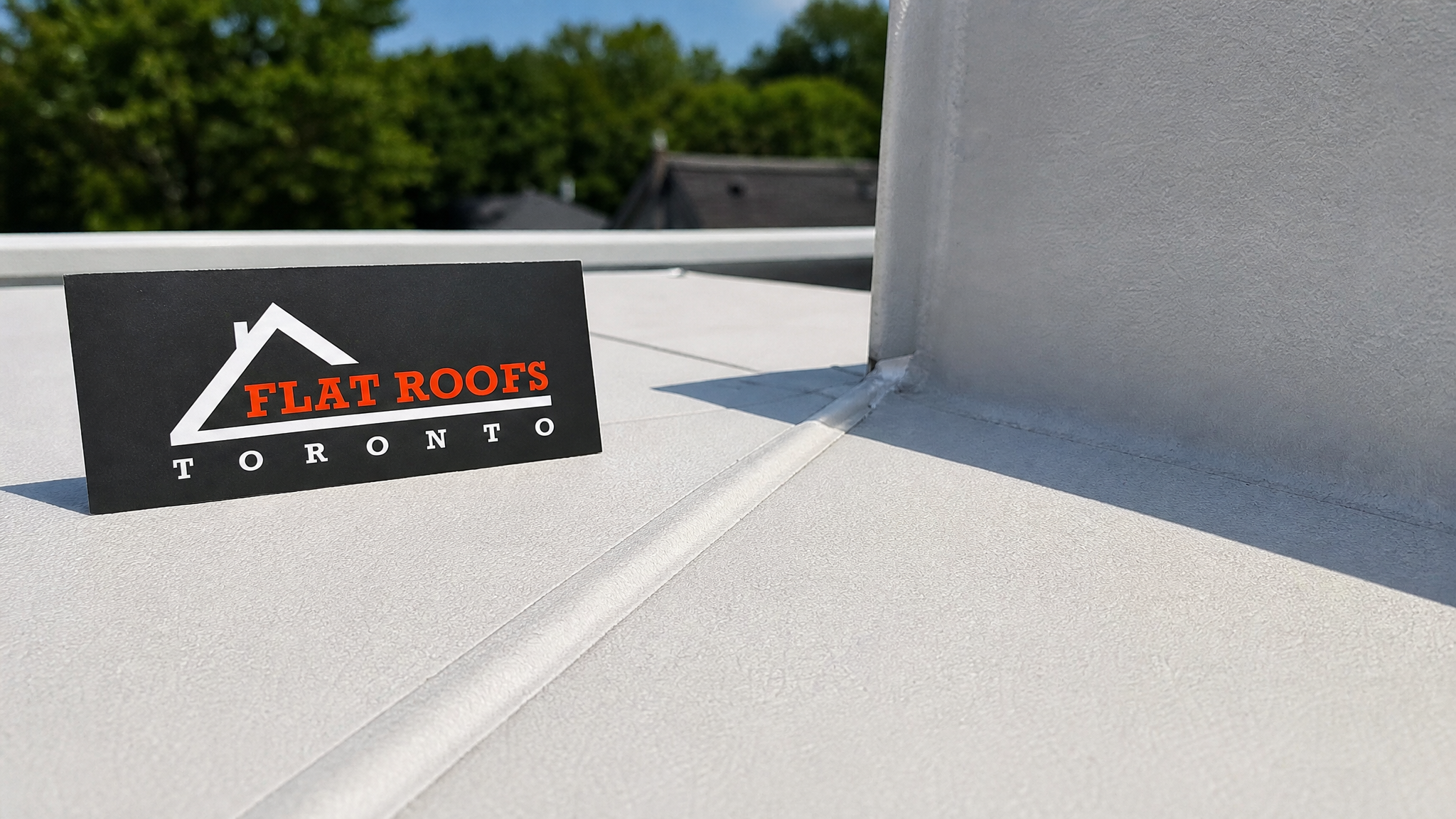 Close-up detail of TPO membrane heat-welded seam on Toronto flat roof re-roof project with branded placard visible